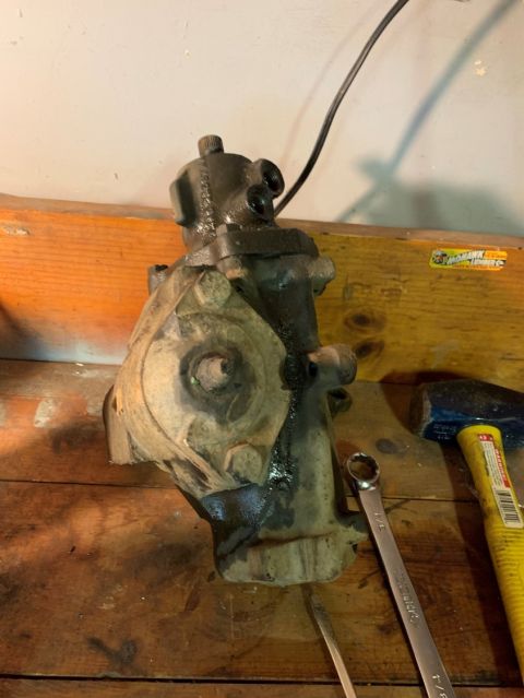 1996 Ford Bronco - A steering gear box sits on a workbench next to a wrench and a hammer.