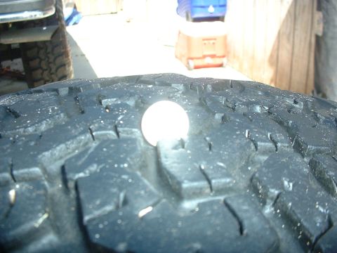 1984 Ford Bronco - Close-up of a tire tread, with a coin placed on it to indicate size.