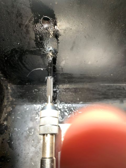 1996 Ford Bronco - A tap wrench is used to create threads in a hole, with metal shavings scattered around the work area.