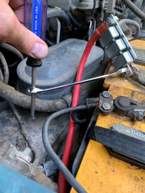 1996 Ford Bronco - Working on engine bay wiring and battery terminals with tools.