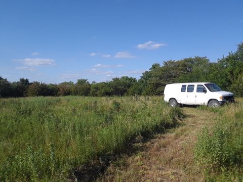 1999 Ford E250 - White 1999 Ford E250 panel van sits in a field under a clear blue sky.