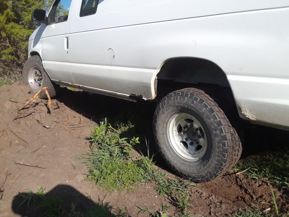 White van side view, off-road tires on dirt