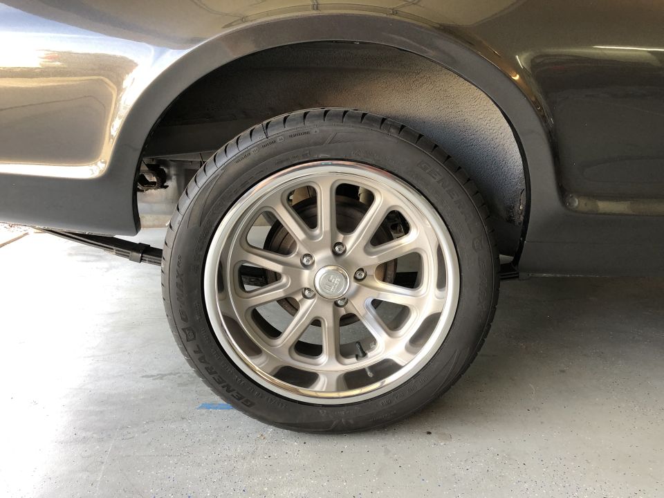 Close-up of a custom five-spoke wheel on a car's rear fender