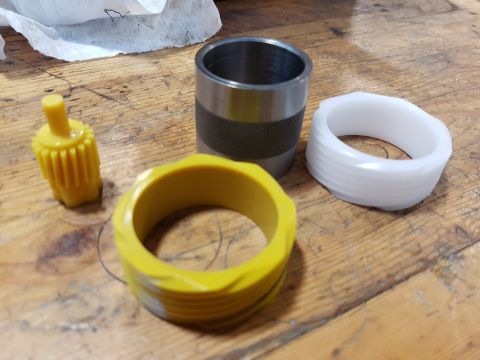 1978 Ford Bronco - Several mechanical parts are laid out on a wooden surface. Visible items include a yellow gear-like piece, a yellow ring with threads, a me…