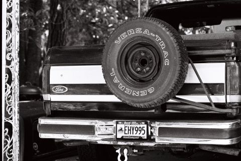 1988 Ford Bronco - The rear of a black and white Ford Bronco is shown, featuring a spare tire mounted on the tailgate and a license plate reading "EHY995". Th…