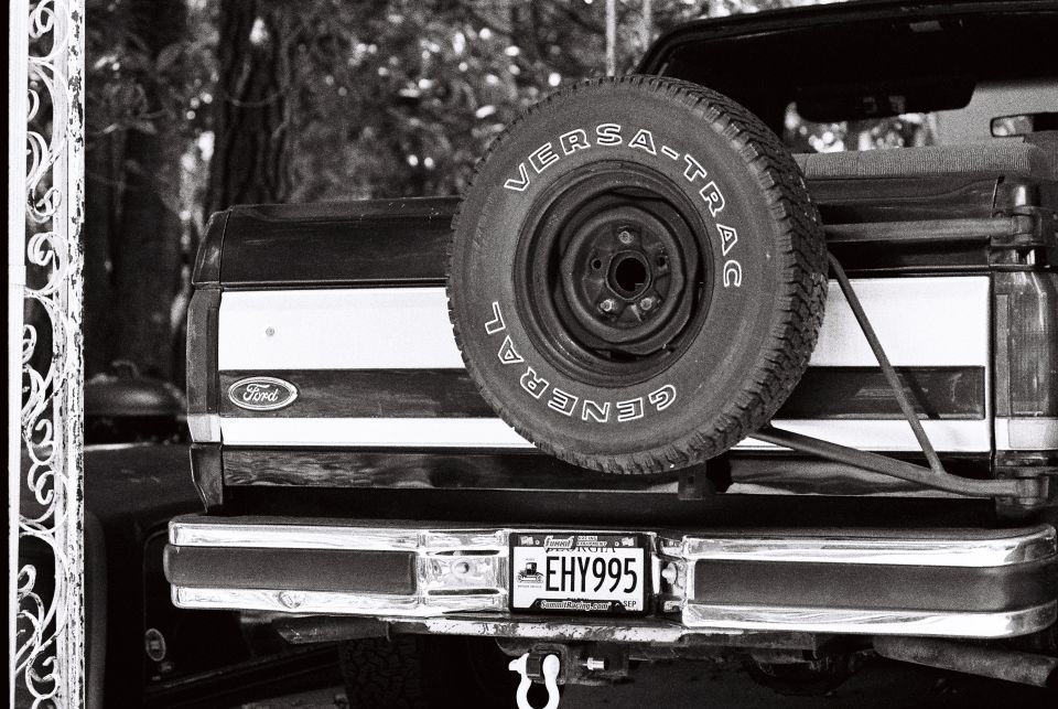 Rear view of a black and white Ford Bronco with spare tire and license plate EHY995.