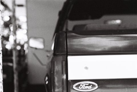 1988 Ford Bronco - The rear of a Ford pickup truck is visible, featuring the Ford oval emblem on the tailgate. The vehicle appears to be in a garage or worksh…