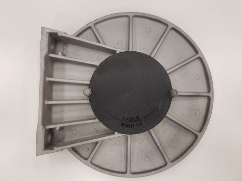 1978 Ford Bronco - This is a close-up, overhead view of a silver metal mounting bracket with a black circular cover. The cover has text that reads "CABLE WIND…