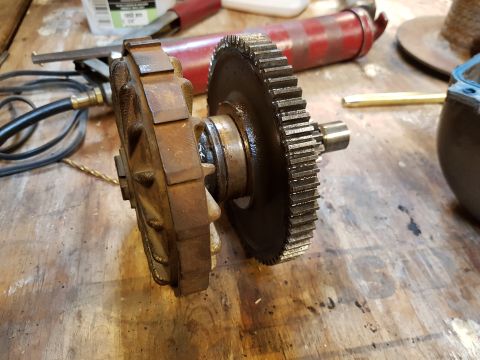 1978 Ford Bronco - A close-up view of a rusty differential gear assembly with a large gear and a smaller, more complex gear on a wooden workbench. Tools and o…