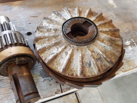 1978 Ford Bronco - Two rusty metal automotive parts are shown on a wooden surface. The part on the left is a splined shaft with a bronze bushing, and the part…
