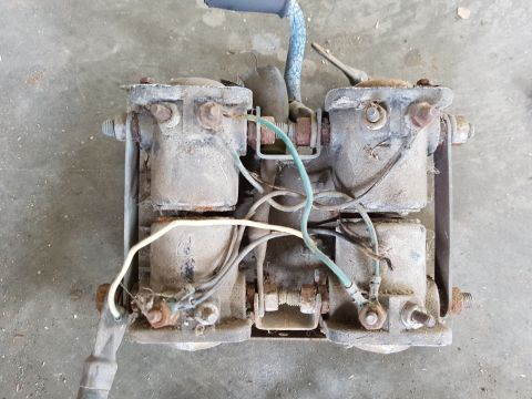1978 Ford Bronco - A dusty, two-part electrical solenoid assembly is mounted on a metal bracket. Wires and bolts are visible connecting the two solenoids.