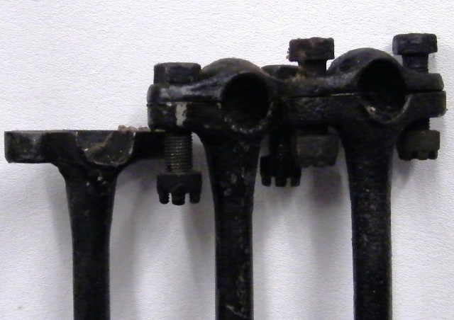 Three black metal automotive parts with clamp-like structures and bolts.