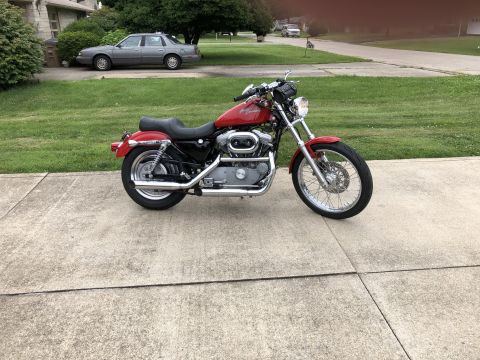 2002 Harley-Davidson Sportster Custom - A red 2002 Harley-Davidson Sportster Custom motorcycle is parked on a concrete driveway.
