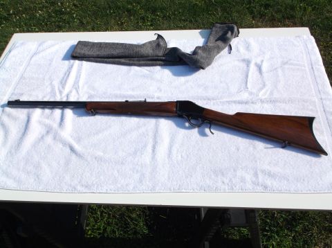 1995 Mercury Grand Marquis - A rifle with a polished wooden stock and dark metal barrel is displayed on a white cloth, with a gray fabric cover nearby.