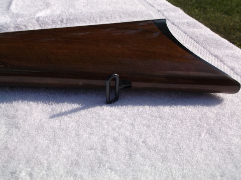 1995 Mercury Grand Marquis - Close-up view of a wooden gun stock with a metal swivel, placed on a towel outdoors.