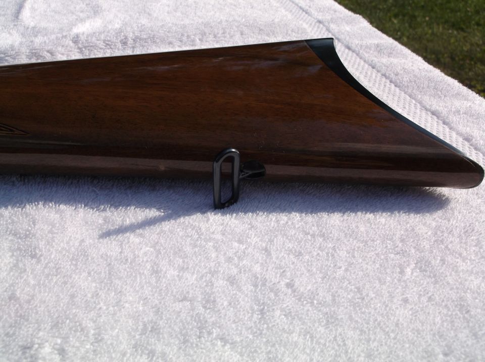 Wooden gun stock with a metal swivel attachment, resting on a white towel