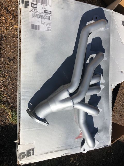 1992 Jeep Wrangler - A silver exhaust manifold is shown resting on a cardboard box outdoors.