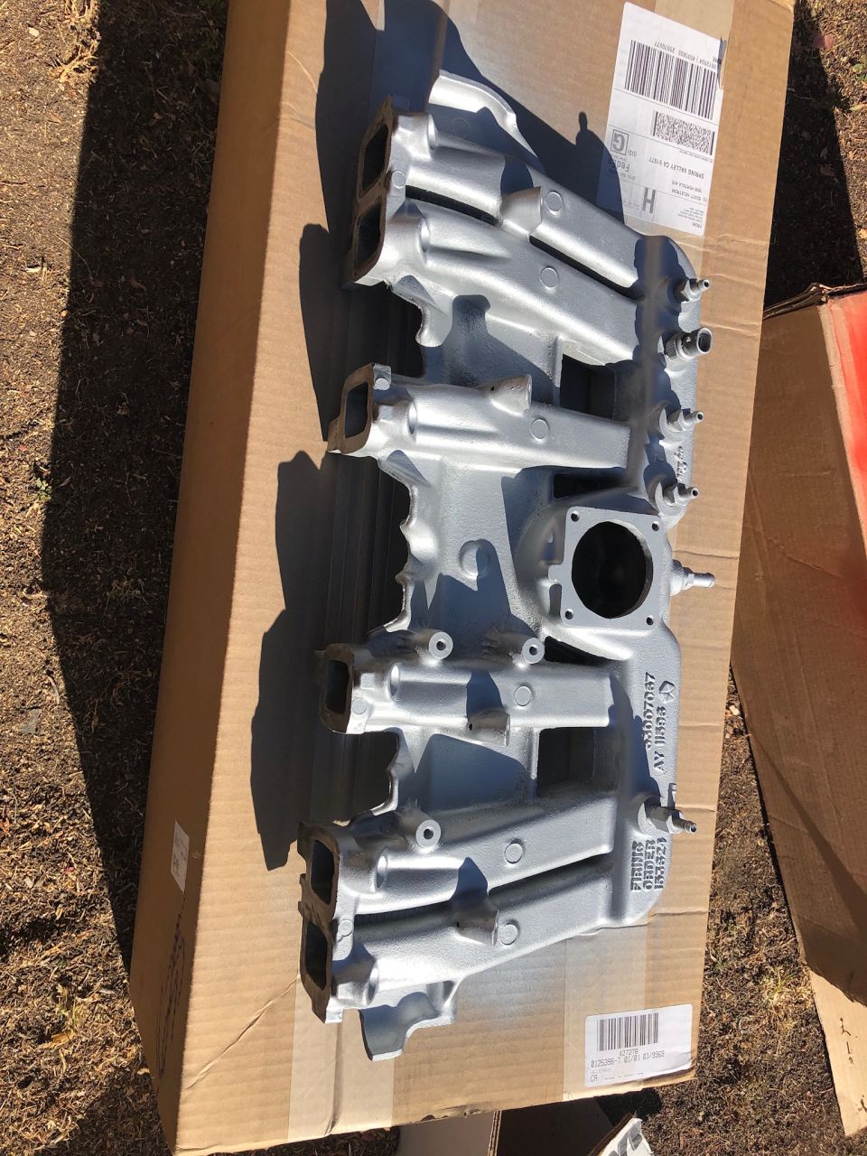 Silver aluminum intake manifold on a cardboard box