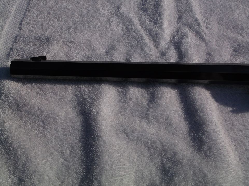 Gun barrel with front sight, resting on a textured surface