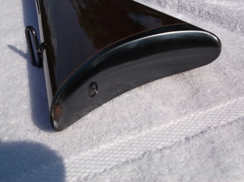 1995 Mercury Grand Marquis - Close-up view of a rifle's dark wood buttstock a black recoil pad and a metal sling swivel.