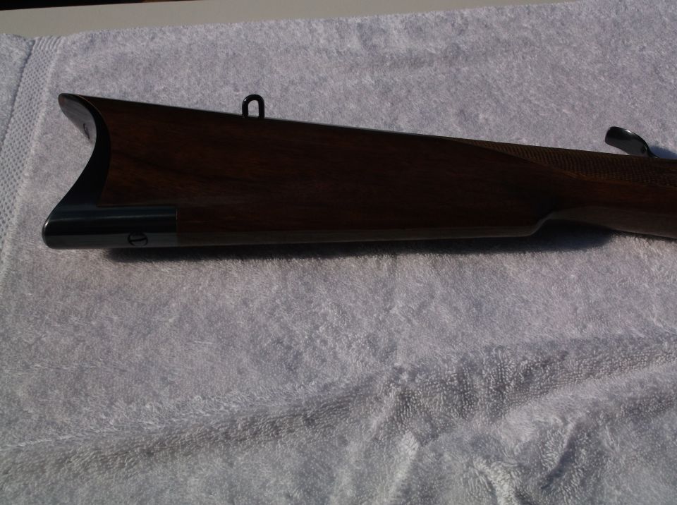 Close-up of a wooden rifle stock with metal accents, resting on a towel