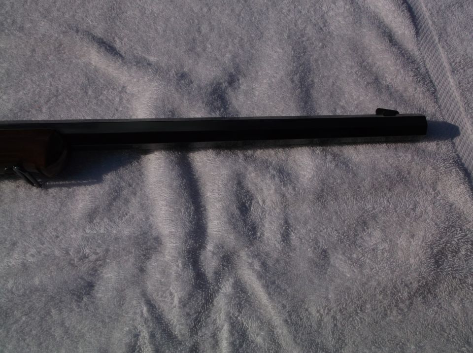 Close-up of a rifle barrel resting on a towel. A Supermotors.net watermark is visible