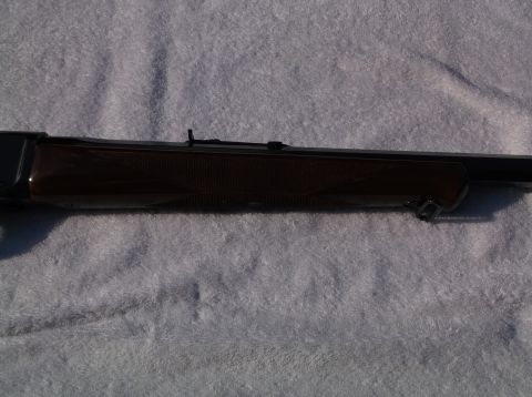 1995 Mercury Grand Marquis - A rifle's receiver and wooden stock are shown in a close-up side view against a textured background.