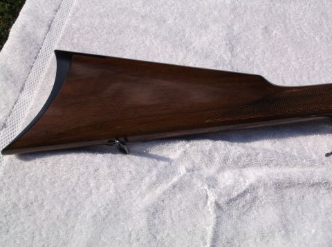 1995 Mercury Grand Marquis - Close-up of a wooden rifle stock, showing the checkered grip and metal hardware.