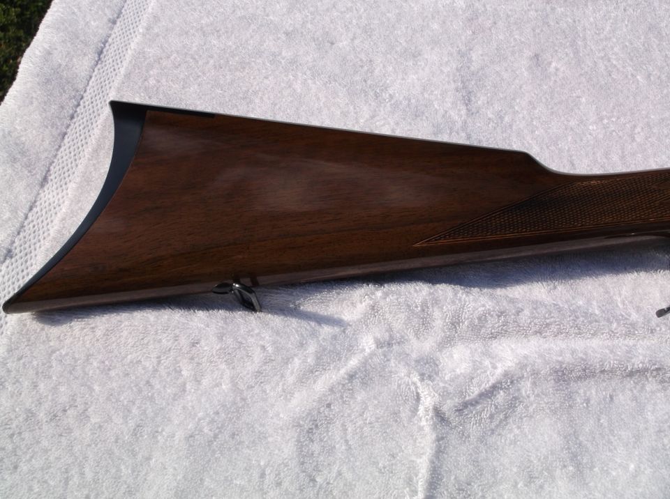 Wooden rifle stock with checkered grip area and metal trigger guard