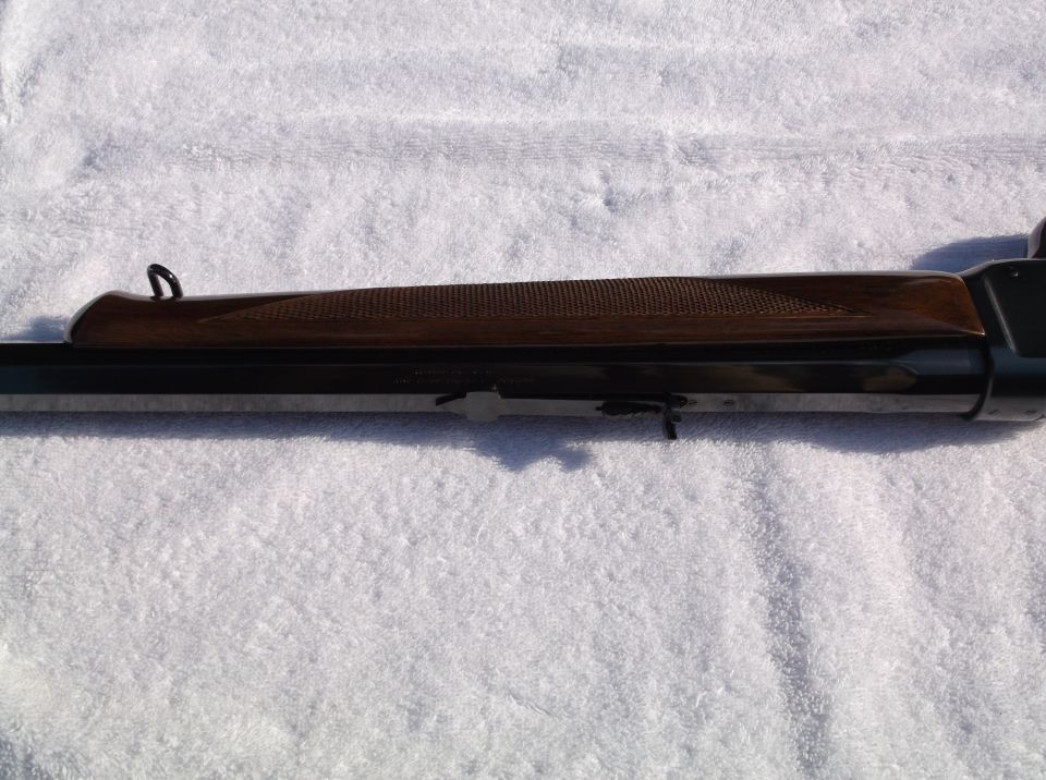 Close-up of a rifle's wooden stock and metal receiver on a white towel