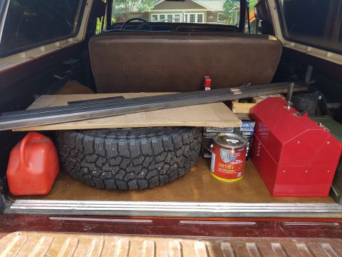 1978 Ford Bronco - Cargo area of a 1978 Ford Bronco loaded with a spare tire, gas can, toolbox, and paint.
