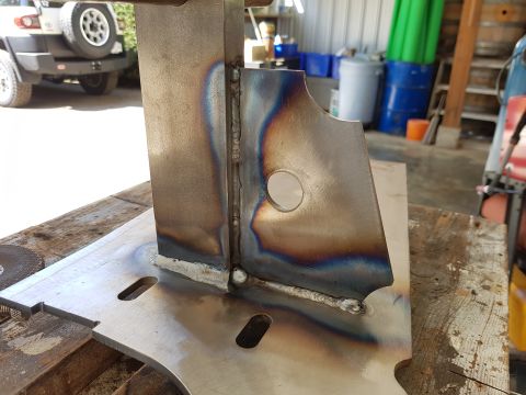 1978 Ford Bronco - A close-up of a welded metal bracket, with a white SUV visible in the background.