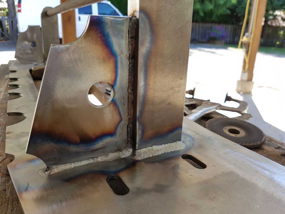 Close-up of a welded metal bracket with heat discoloration and a circular cutout
