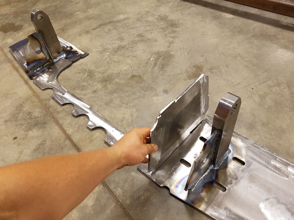 Hand holding a custom-welded metal bracket with mounting holes
