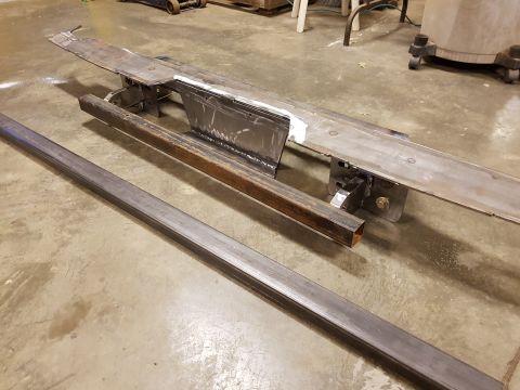 1978 Ford Bronco - Metal frame components are laid out on a workshop floor, suggesting repair or fabrication work.