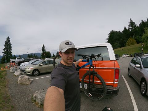 1978 Ford Bronco - A man stands next to an orange 1978 Ford Bronco with a bicycle mounted on the rear rack in a parking lot.