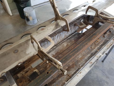 1978 Ford Bronco - A metal frame section, likely part of a vehicle chassis, is secured with clamps for welding or repair work.