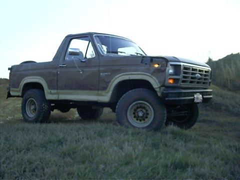 1985 Ford Bronco - This 1980s Ford Bronco is shown from the front quarter angle on a grassy incline.