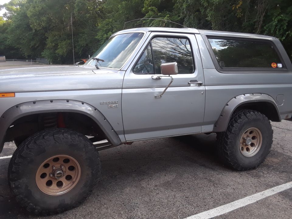 Silver Ford Bronco parked outside, lifted with large tires