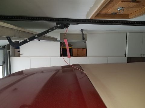 1985 Ford Bronco - A red car roof and a tan roof panel are visible in a garage setting.