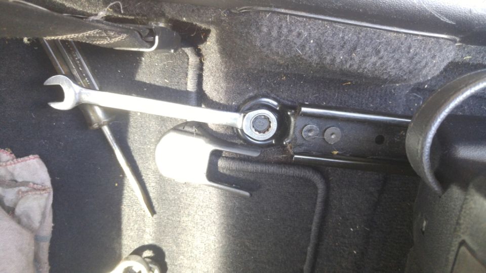 Seat bolt being loosened with a wrench inside a vehicle