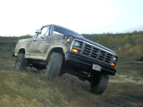 1985 Ford Bronco - Ford Bronco navigating rough terrain on a dirt hill.