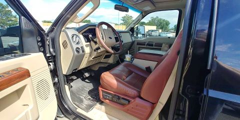 2010 Ford F-250 - The interior of a truck with a Ford logo on the steering wheel and brown leather seats is visible.
