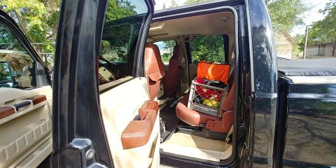 2010 Ford F-250 - Interior of a black pickup truck with tan upholstery and a crate of items in the rear seat.