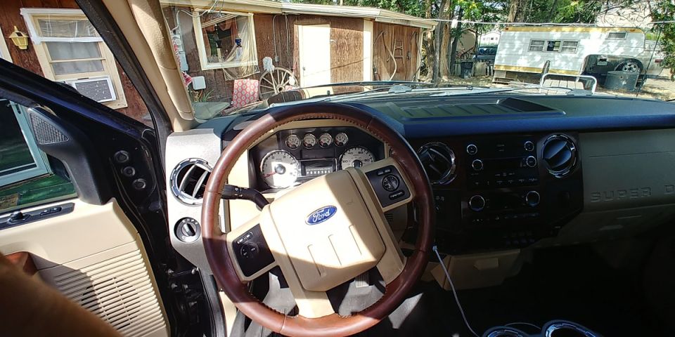 Interior of a Ford Super Duty truck, showing the dashboard, steering wheel, and center console. The 'SUPER DUTY' badge is visible