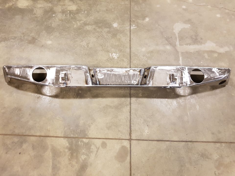 Chrome rear bumper with cutouts for exhaust pipes, mounted on concrete floor
