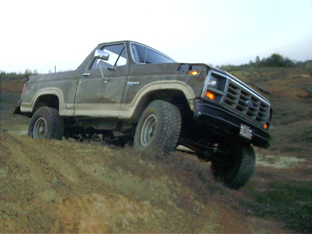 Brown Ford Bronco with white trim stuck in mud, front 3/4 view