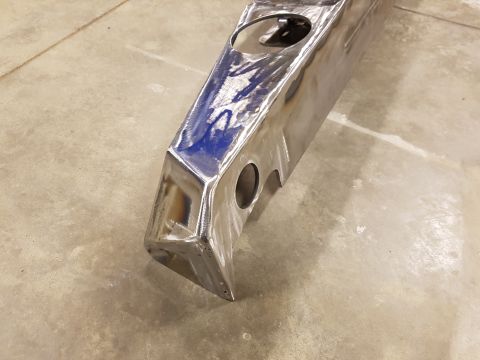 1978 Ford Bronco - A raw metal component, possibly a bumper or frame section, sits on a concrete floor.