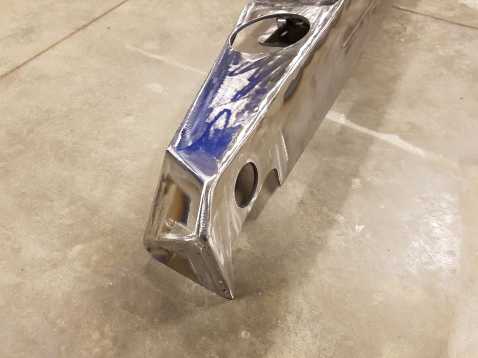 Unfinished metal part with two circular cutouts and a blue-marked surface, viewed from an angle