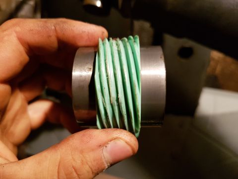 1978 Ford Bronco - A hand holds a green worm gear, showing its helical teeth and metal shaft.